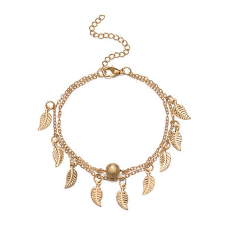 Gold bracelet with leaf charms on a white background