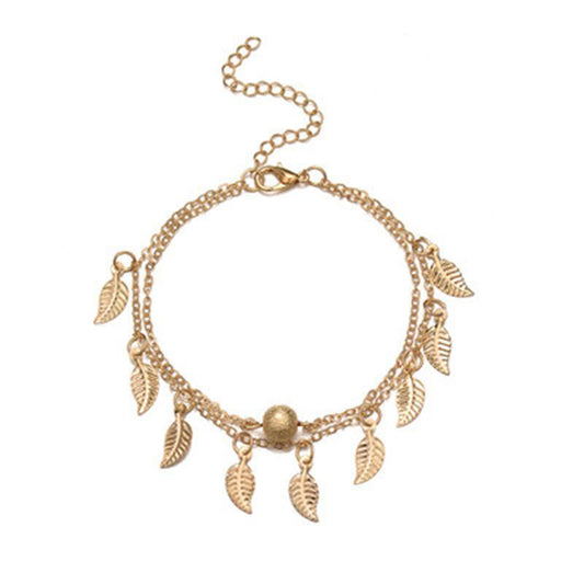 Gold bracelet with leaf charms on a white background