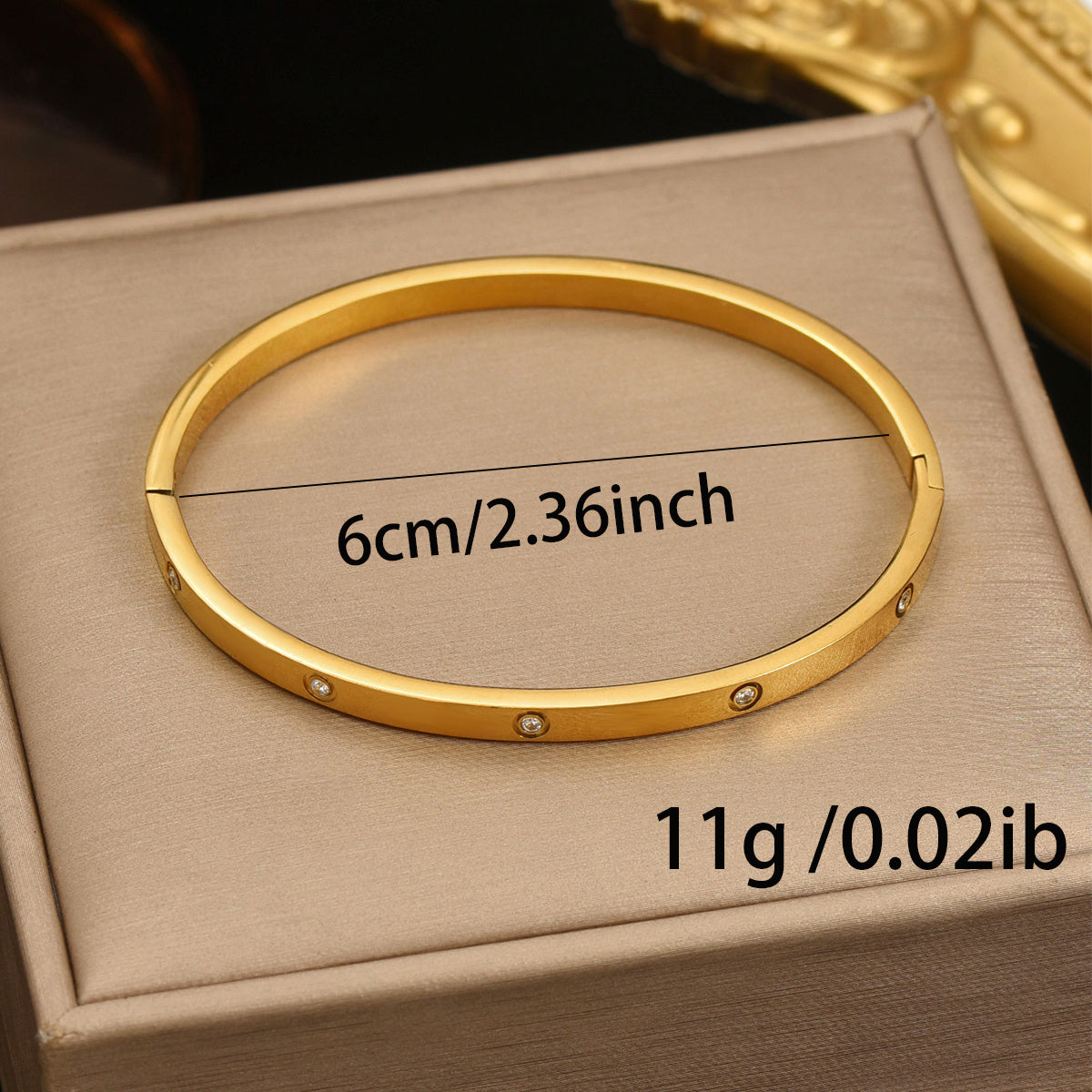 Gold bracelet on a beige box with measurements displayed