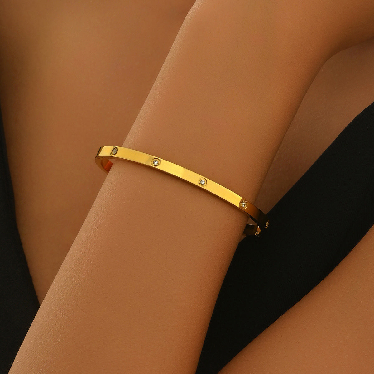 Gold bracelet on a wrist with a plain background