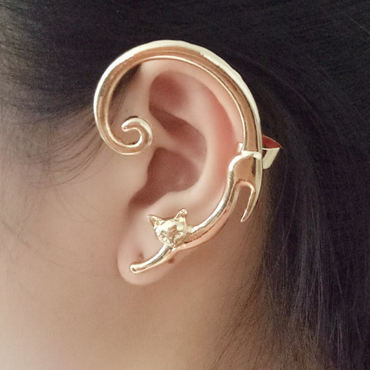 Gold cat-shaped ear cuff worn on an ear with a blurred background