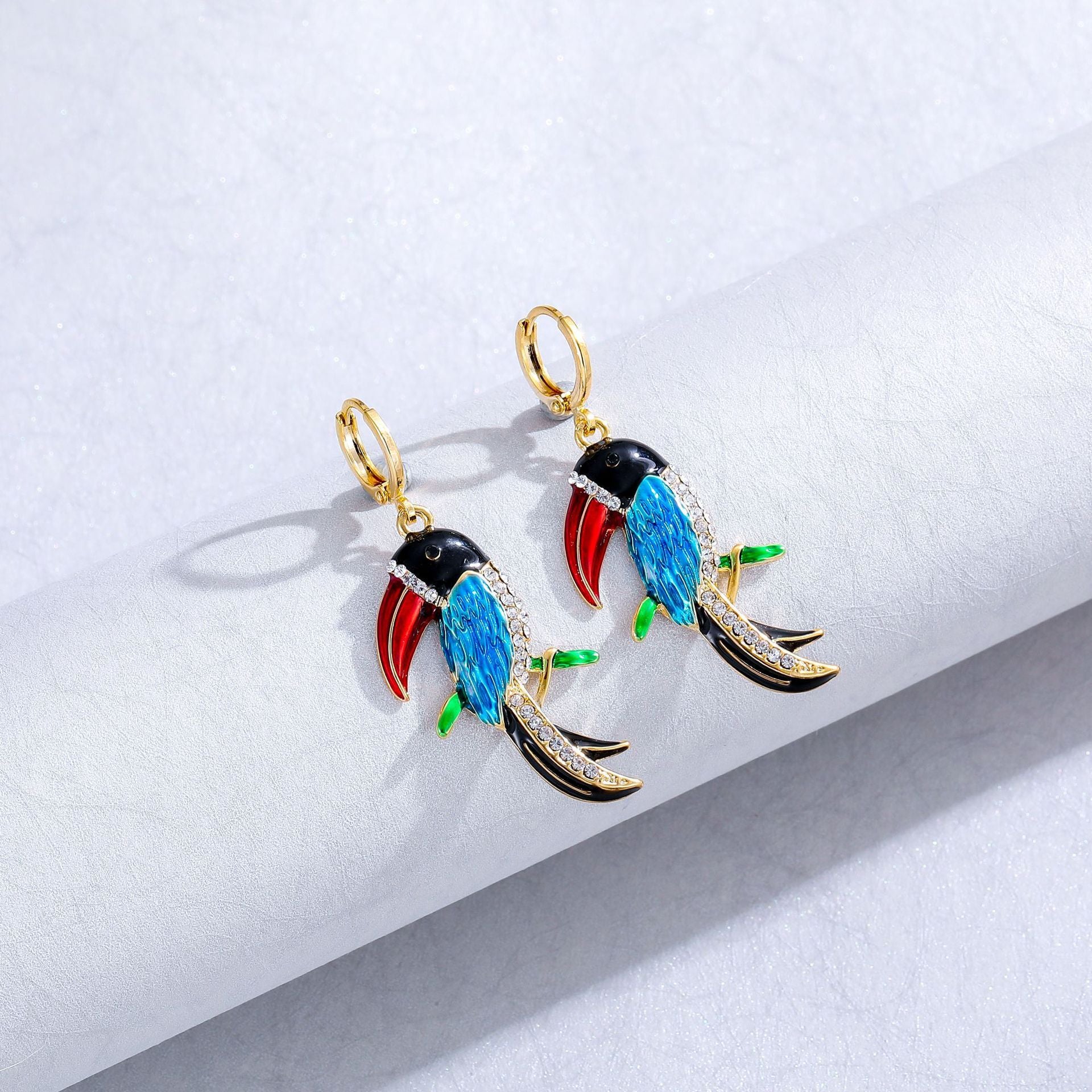 Colorful bird-shaped earrings on a light gray background