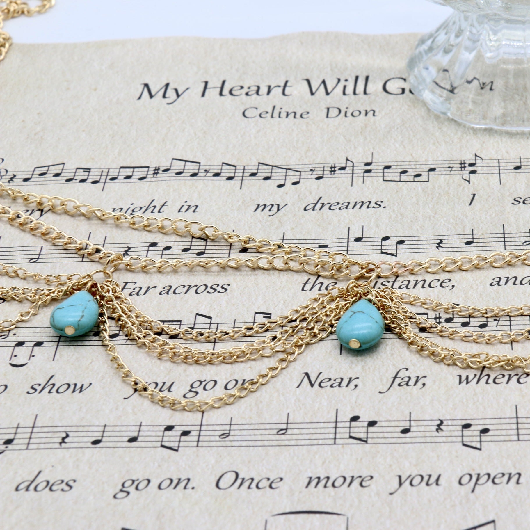 Gold chain necklace with turquoise beads on sheet music