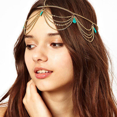 Woman wearing a gold chain headpiece with green accents on a white background