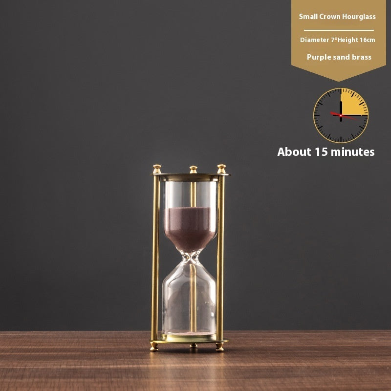 Small crown hourglass with purple sand on a wooden surface and dark background