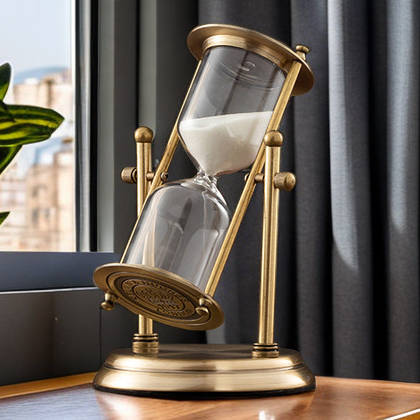 Decorative sand timer with gold frame on a table near a window