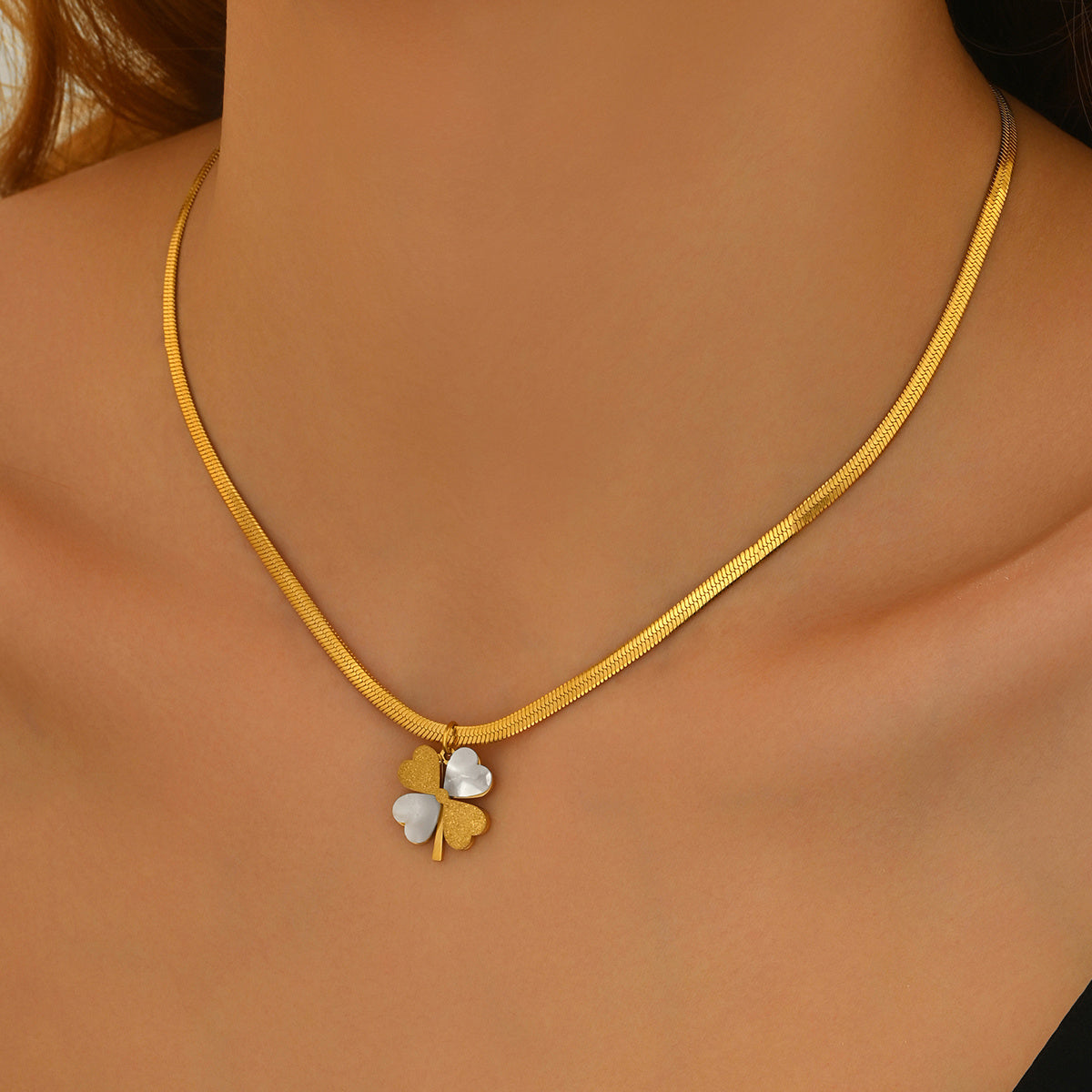 Gold necklace with a clover-shaped pendant on a model