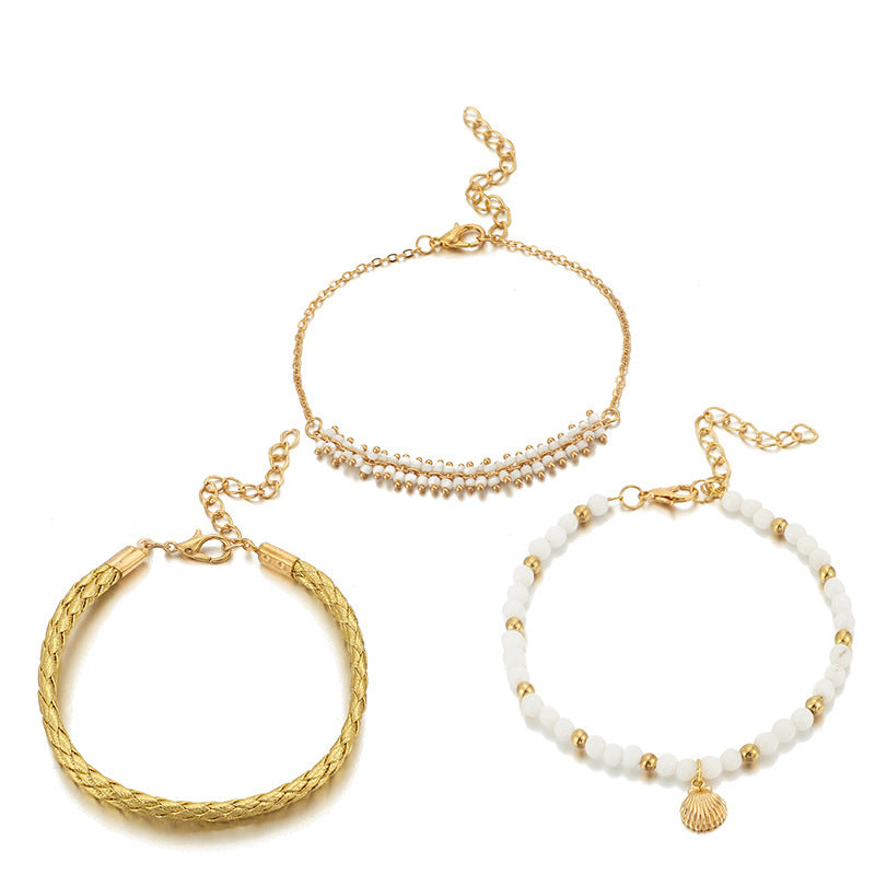 Three gold and white beaded bracelets on a white background