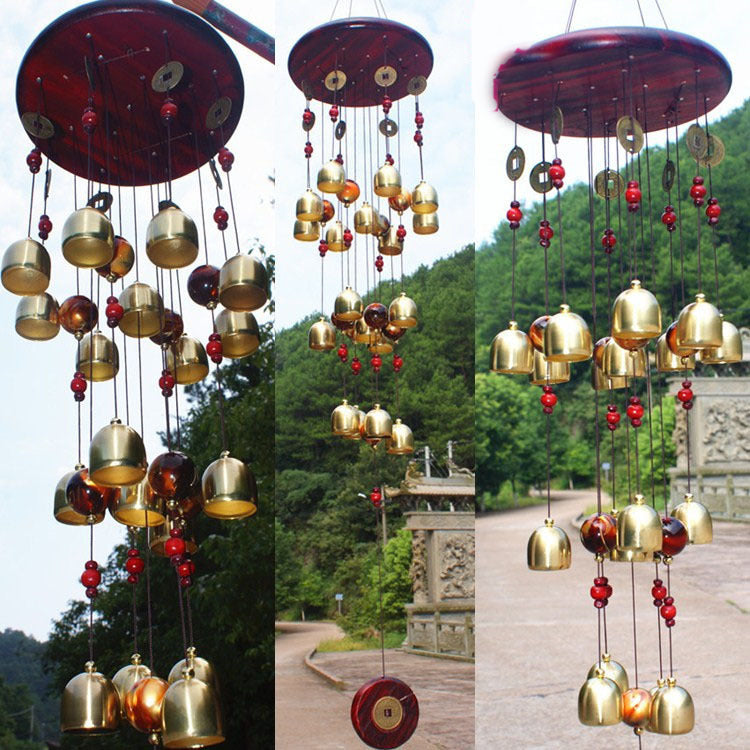 Decorative wind chime with gold and red elements in a natural setting.