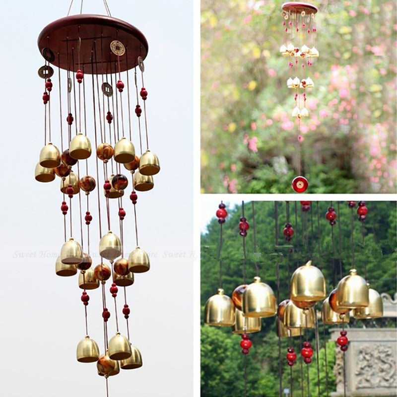Gold wind chime with red beads against a blurred natural background