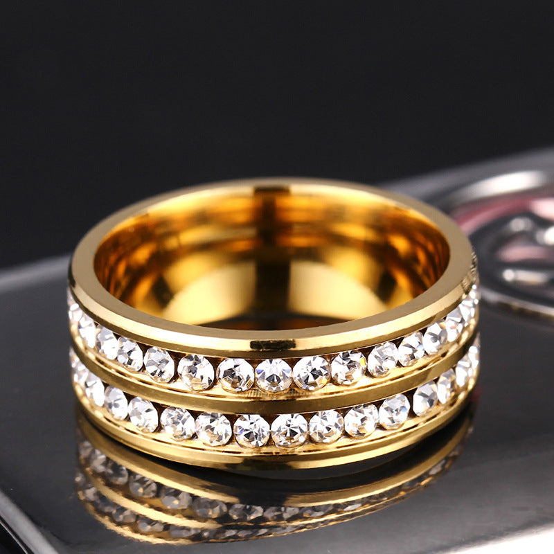 Gold ring with diamond-studded bands on a reflective surface
