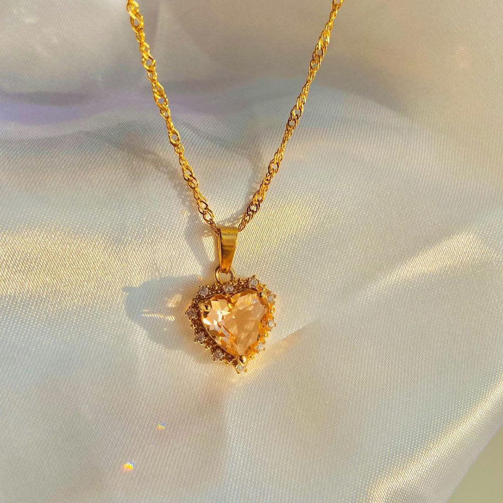 Gold necklace with a heart-shaped pendant on a light fabric background