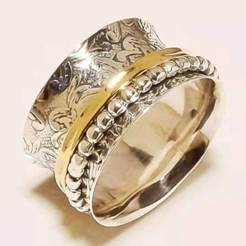 Gold and silver ring with intricate designs on a light background