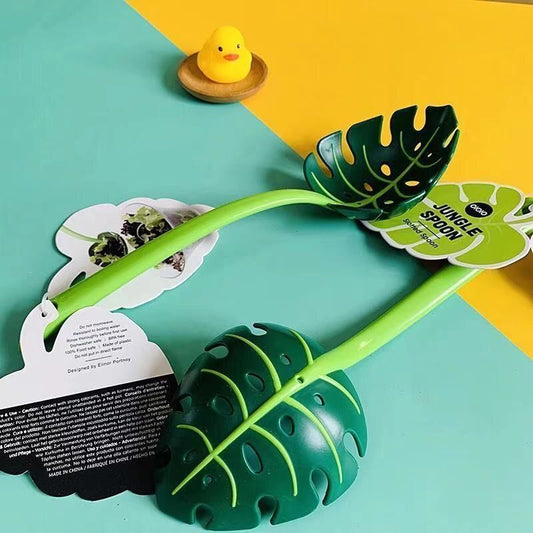 Green leaf-shaped spoon on a colorful background with a small yellow duck toy.