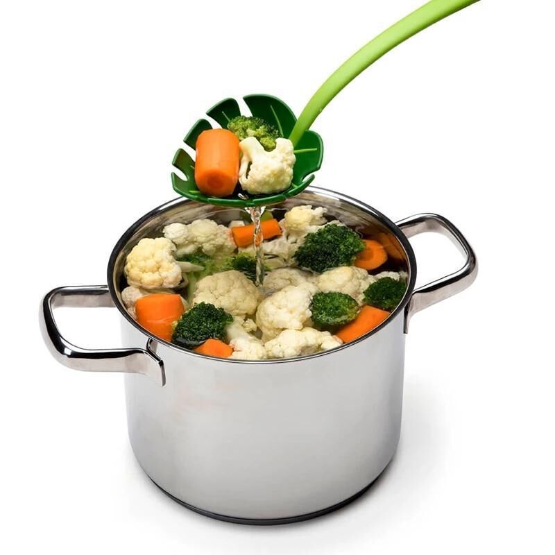 Vegetable peeler being used to peel vegetables into a pot on a white background