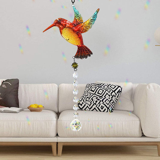 Colorful hummingbird-shaped decorative hanging item on a light gray sofa with patterned cushions.