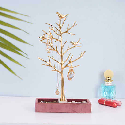 Gold jewelry tree with hanging earrings on a light blue background