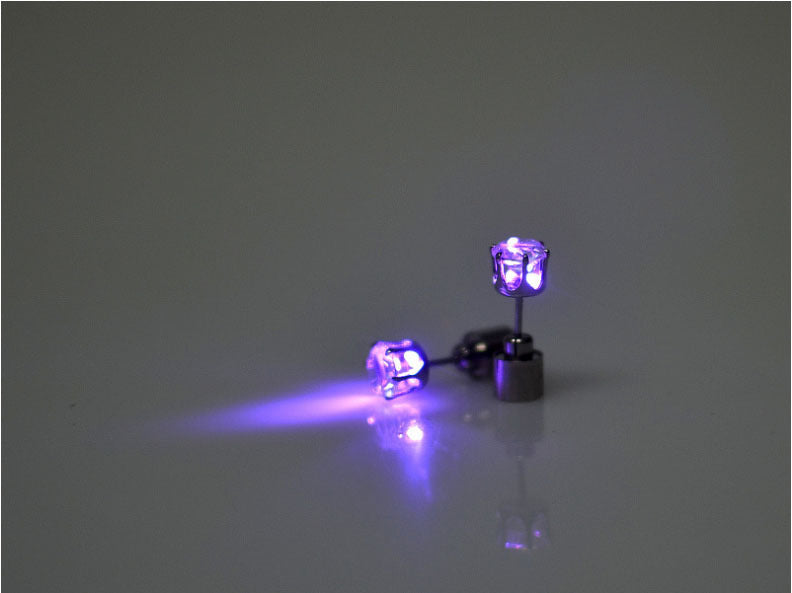 Purple LED light-up earrings on a reflective surface with a dark background