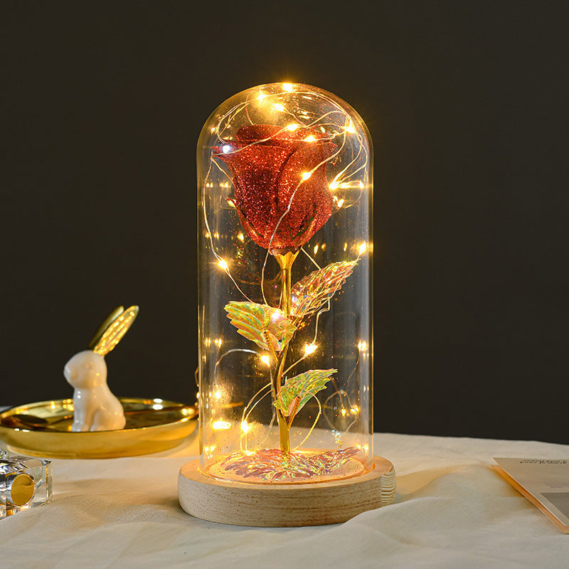 Decorative rose inside a glass dome with lights on a dark background