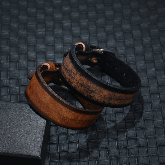 Two leather bracelets, one brown and one black, on a textured dark surface.