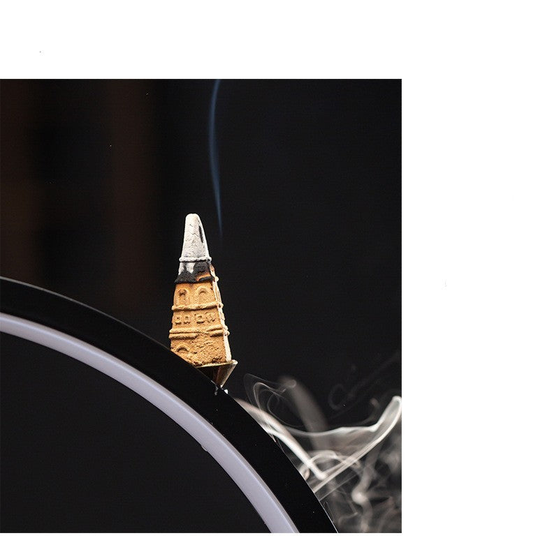 Close-up of a lit incense cone with smoke against a dark background