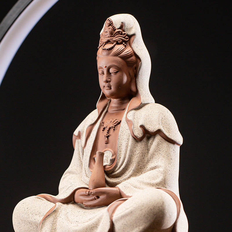 Statue of a seated figure with a white robe and head covering on a black background