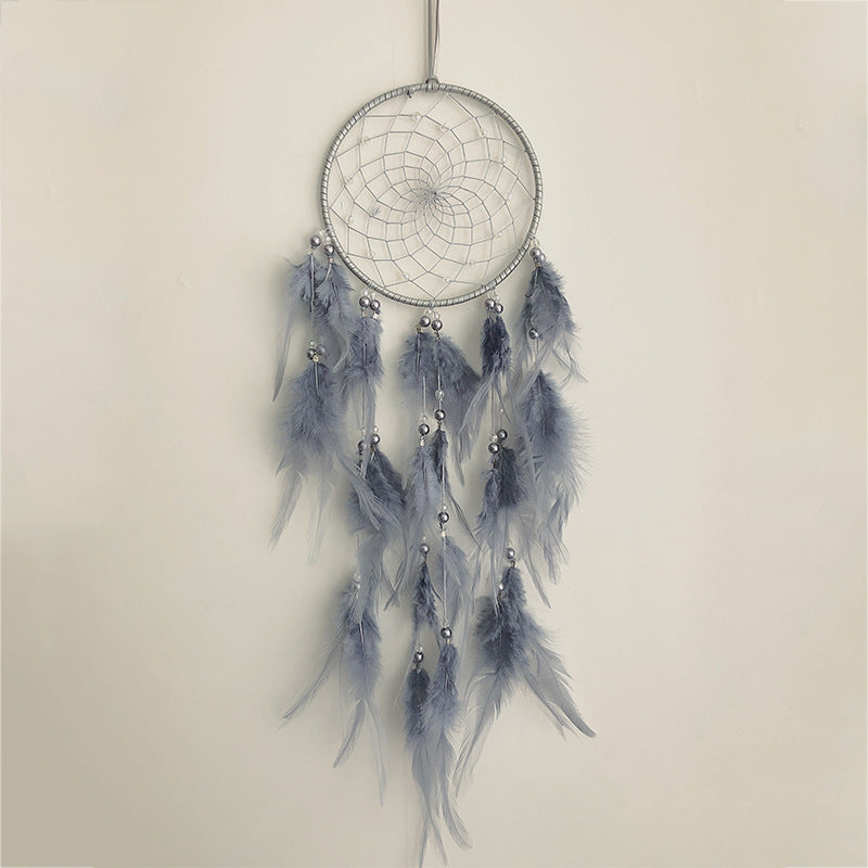 Dreamcatcher with feathers and beads on a beige background