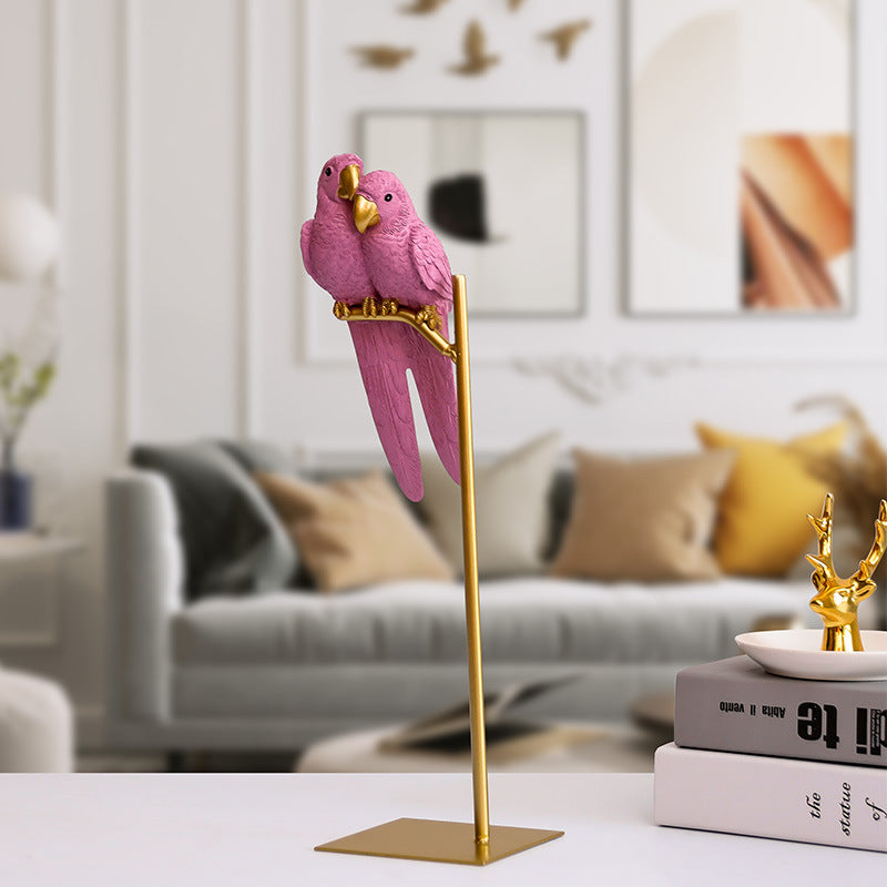 Decorative pink parrot sculpture on a gold stand in a living room setting