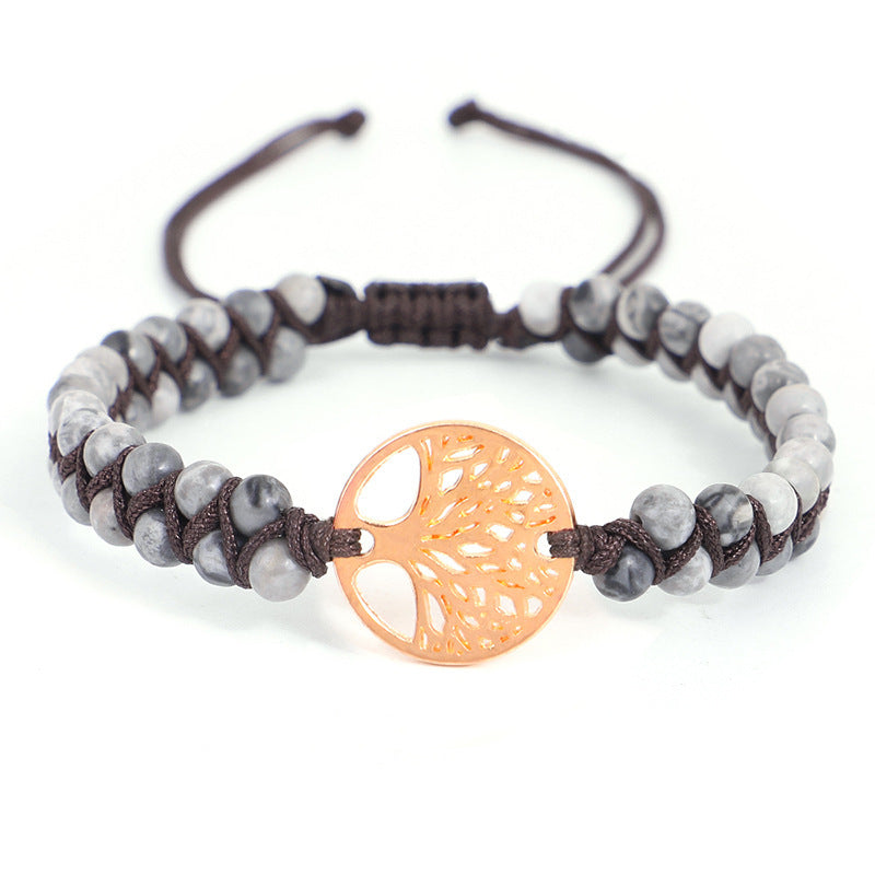 Bracelet with gray beads and a rose gold tree-of-life charm on a white background