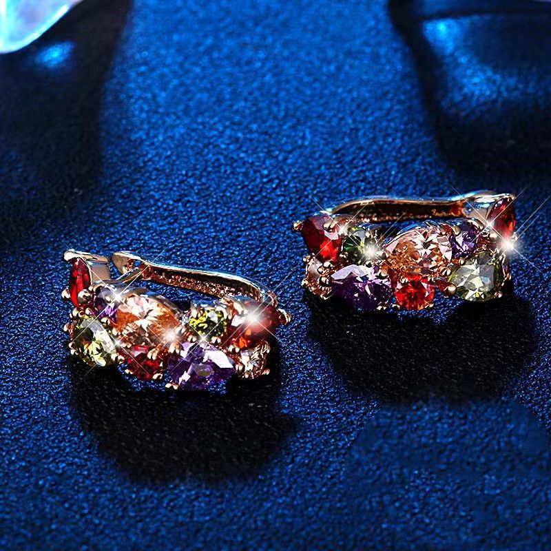 Colorful gemstone earrings on a dark blue textured surface