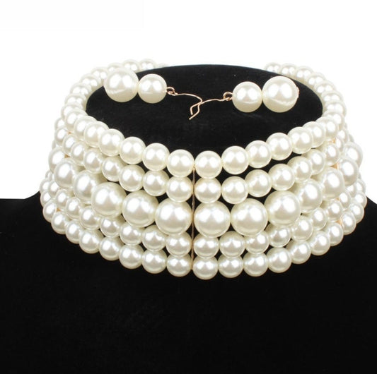 Multiple layers of pearl necklace on a black stand with a white background
