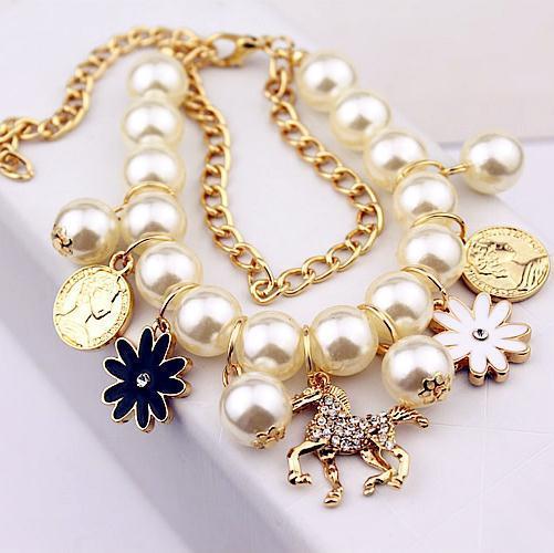 Necklace with pearl beads and various charms on a white background