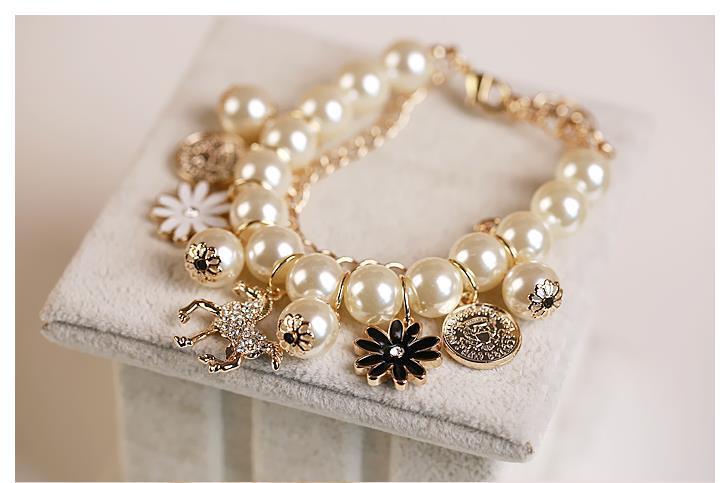 Pearl bracelet with decorative charms on a white surface