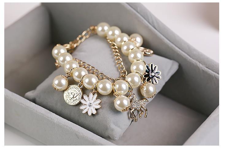 Pearl bracelet with gold accents and charms on a gray surface