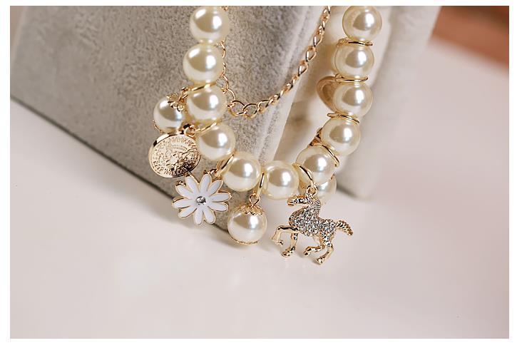 Pearl necklace with gold accents and charms on a light background