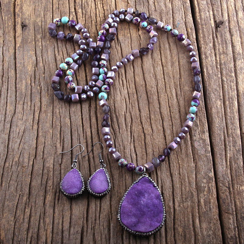 Purple beaded necklace and earrings on a wooden surface
