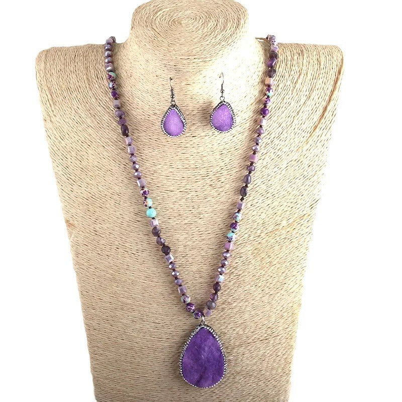 Purple beaded necklace and earrings on a beige mannequin bust.