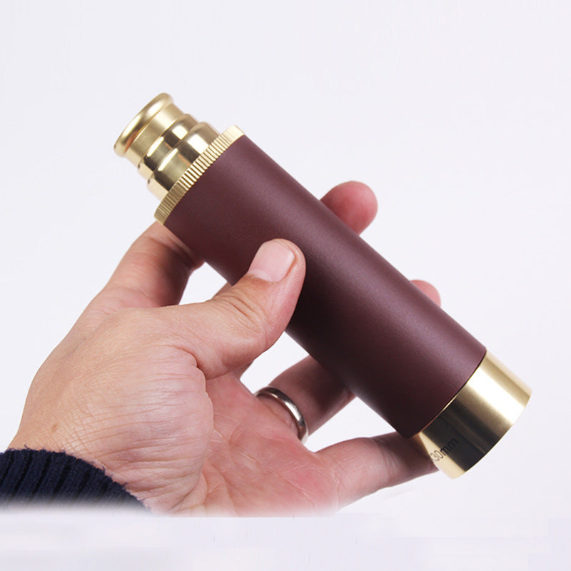 Hand holding a brown and gold cylindrical object against a white background