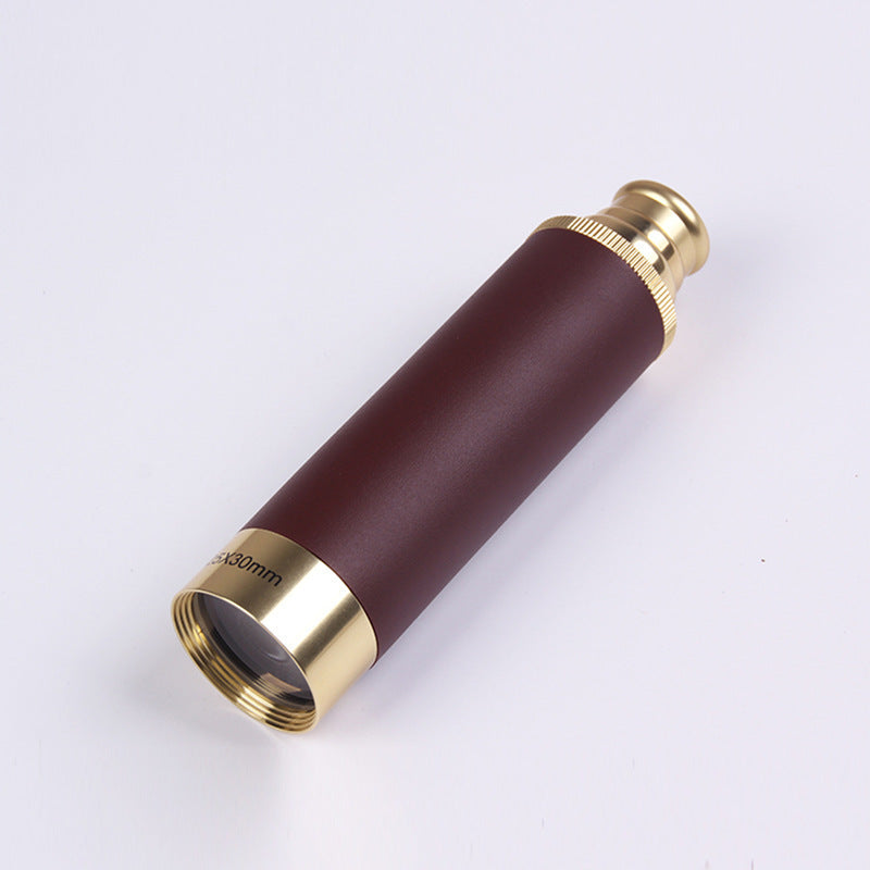 Monocular with burgundy body and gold accents on a white background