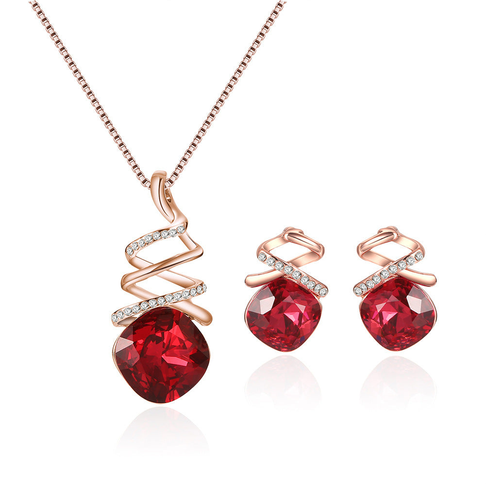 Jewelry set with red gemstones and rose gold accents on a white background