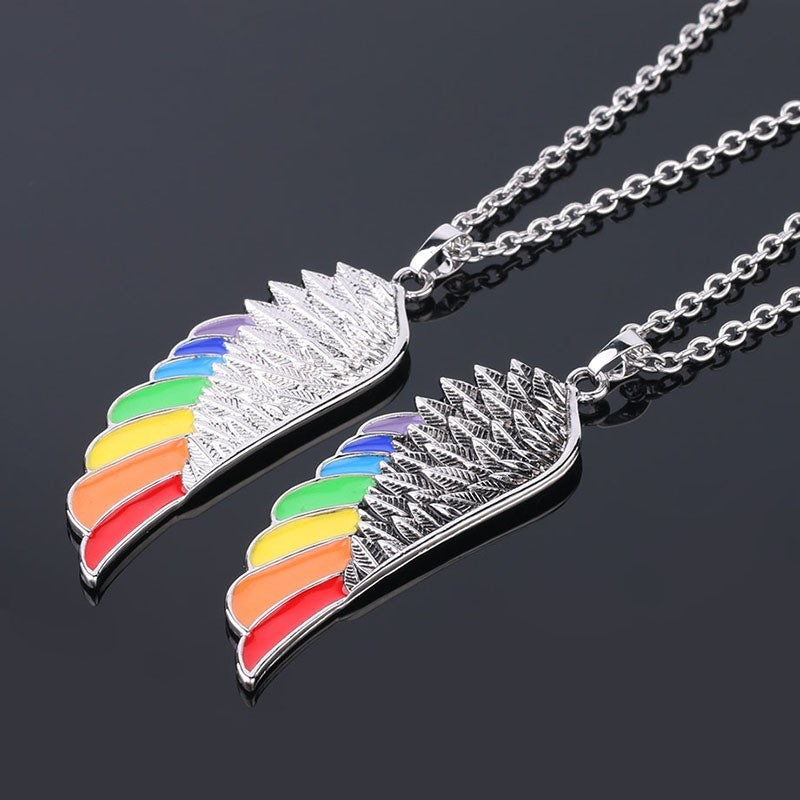 Two rainbow feather-shaped pendants on silver chains against a black background