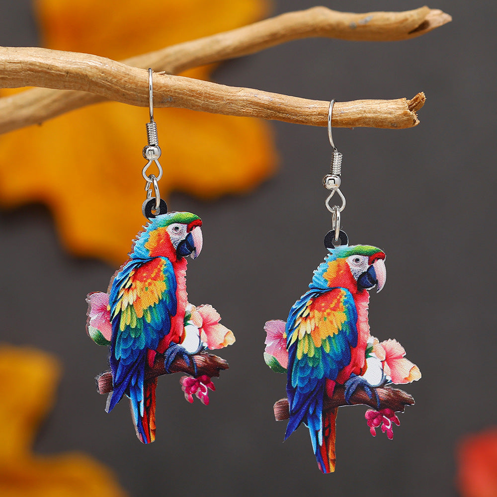 Colorful parrot earrings on a branch with a blurred background