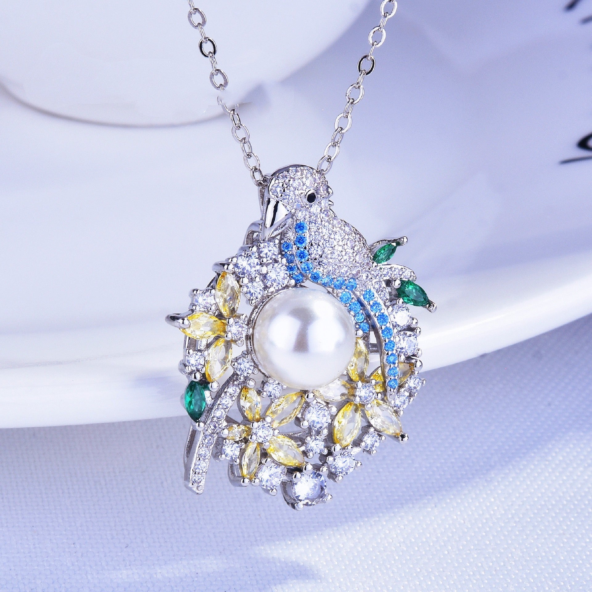 Elegant necklace with a pearl pendant and gemstones on a white background