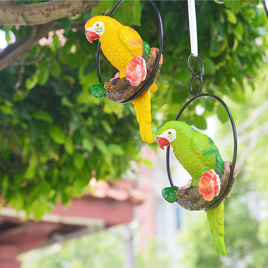 Two parrot-shaped garden ornaments hanging from a tree