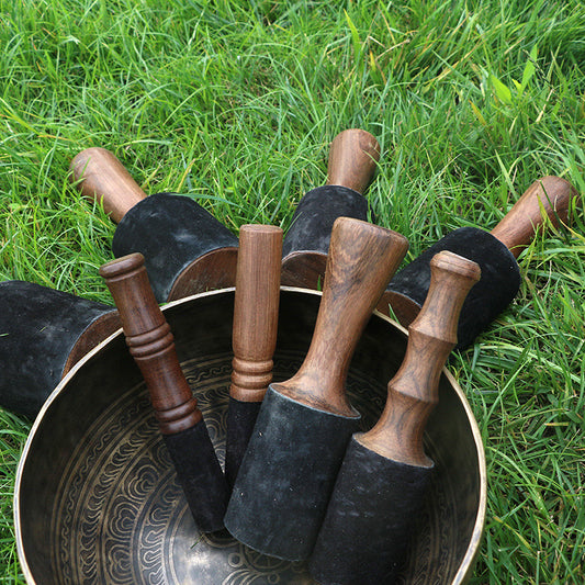 Set of wooden mallets with black handles on a large metal bowl on grass
