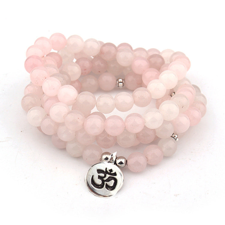 Stack of pink beaded bracelets with a silver Om pendant on a white background