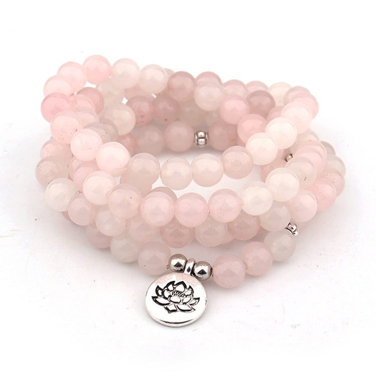 Stack of pink beaded bracelets with silver lotus charm on a white background