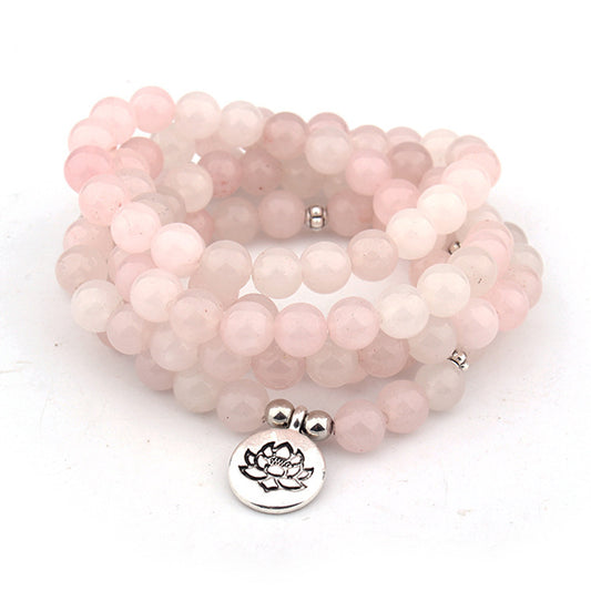 Stack of pink beaded bracelets with silver lotus charm on a white background