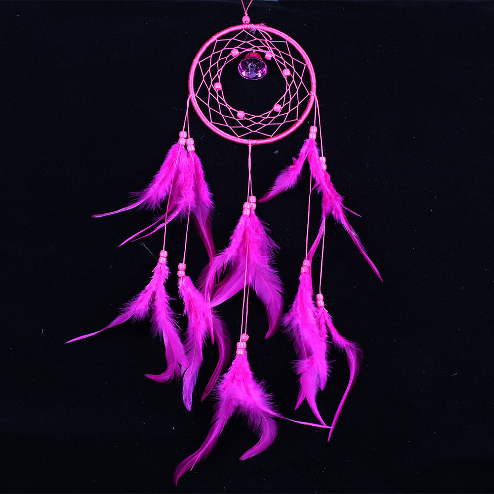 Pink dreamcatcher with feathers on a black background