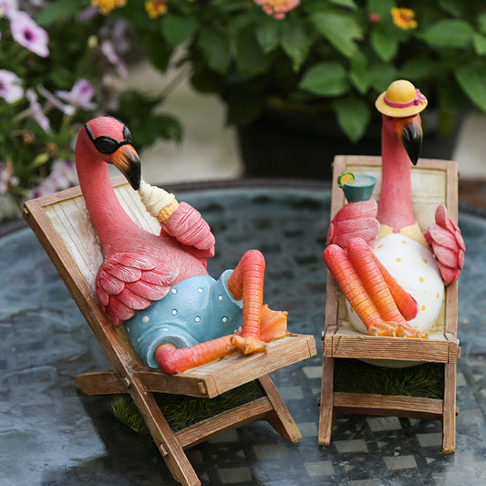 Two pink flamingo figurines lounging on chairs with a scenic background